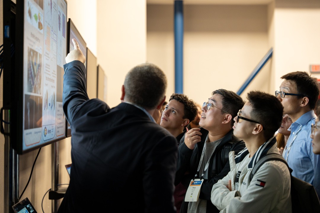 Attendees interact at a scientific poster. 